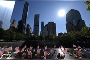 Bandeiras dos Estados Unidos e flores são deixadas junto aos nomes das vítimas no Memorial do 11 de Setembro, em Nova York.