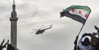 Helic&oacute;ptero militar lan&ccedil;a flores e confetes sobre multid&atilde;o comemorando os dez anos da vit&oacute;ria de for&ccedil;as rebeldes sobre o ex&eacute;rcito de Bashar al-Assad em Idlib, S&iacute;ria, em 28 de mar&ccedil;o de 2025. Foto: &copy; Ghaith Alsayed / АР / RFI